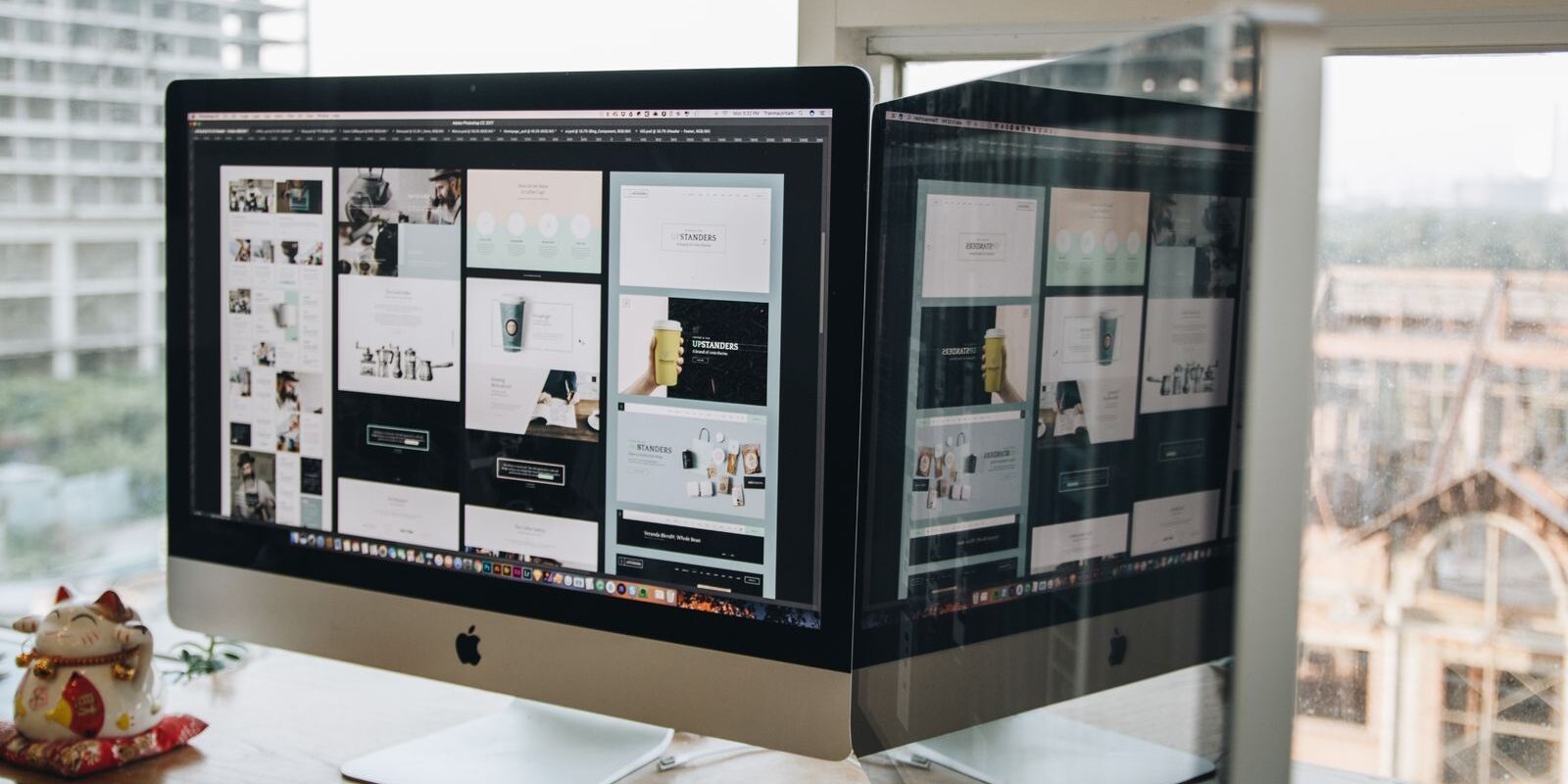Dos monitores sobre un escritorio mostrando el diseño de un sitio web