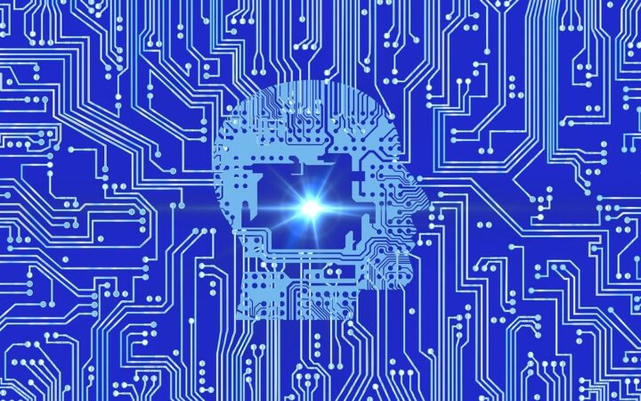 Silueta de una cabeza humana formada por pistas de circuito impreso sobre un fondo azul, con un punto de luz brillante al centro
