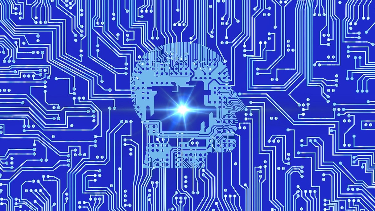 Silueta de una cabeza humana formada por pistas de circuito impreso sobre un fondo azul, con un punto de luz brillante al centro