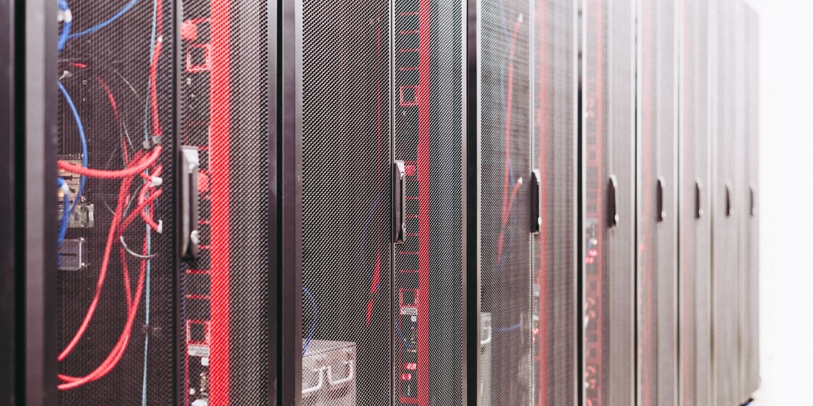Fila de gabinetes de servidores con cables rojos y azules en un centro de datos