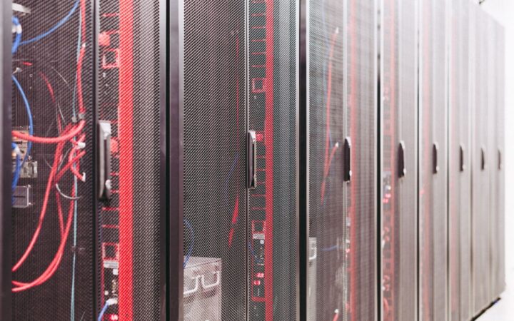 Fila de gabinetes de servidores con cables rojos y azules en un centro de datos