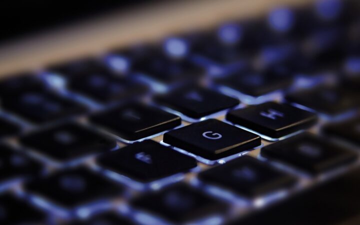 Teclado de computadora con retroiluminación azul visto de cerca, con la tecla G enfocada