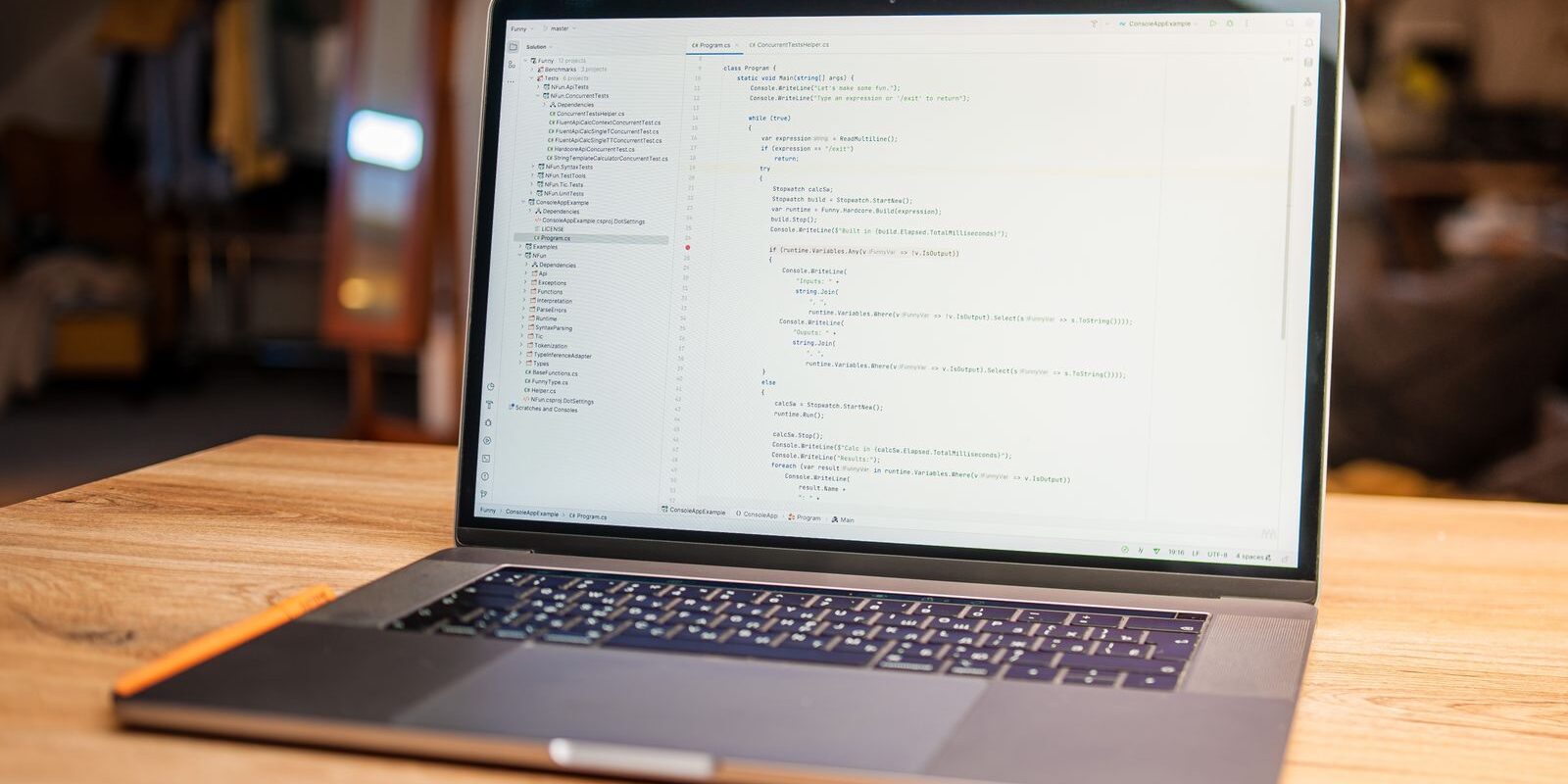 Laptop abierta con código en pantalla sobre un escritorio de madera en un espacio de trabajo con poca luz