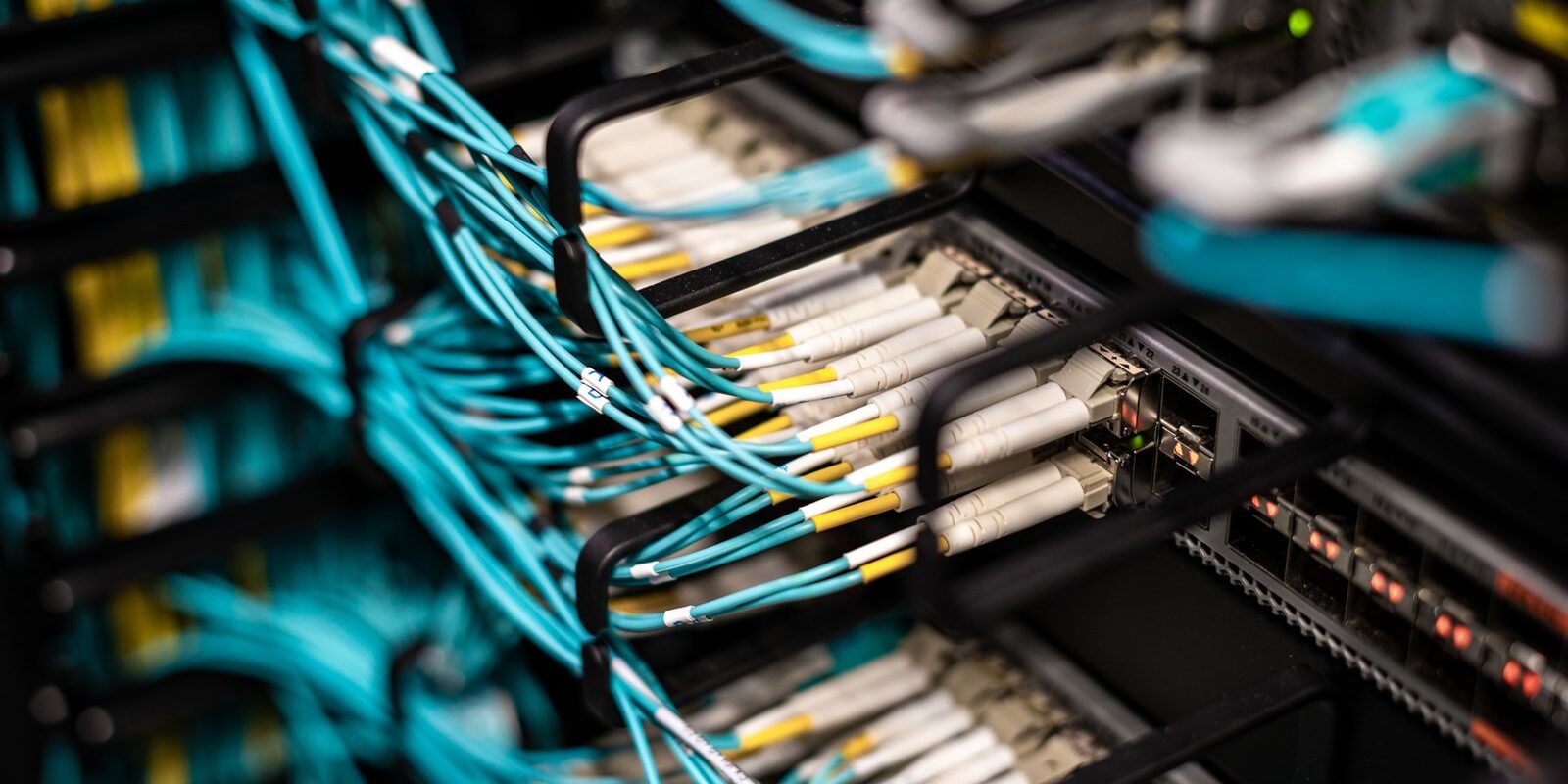 Cables de fibra óptica color turquesa conectados a los paneles de un servidor en un centro de datos
