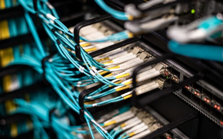 Cables de fibra óptica color turquesa conectados a los paneles de un servidor en un centro de datos