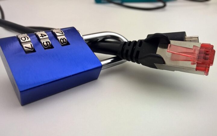 Candado azul de combinación junto a un cable de red sobre una mesa blanca