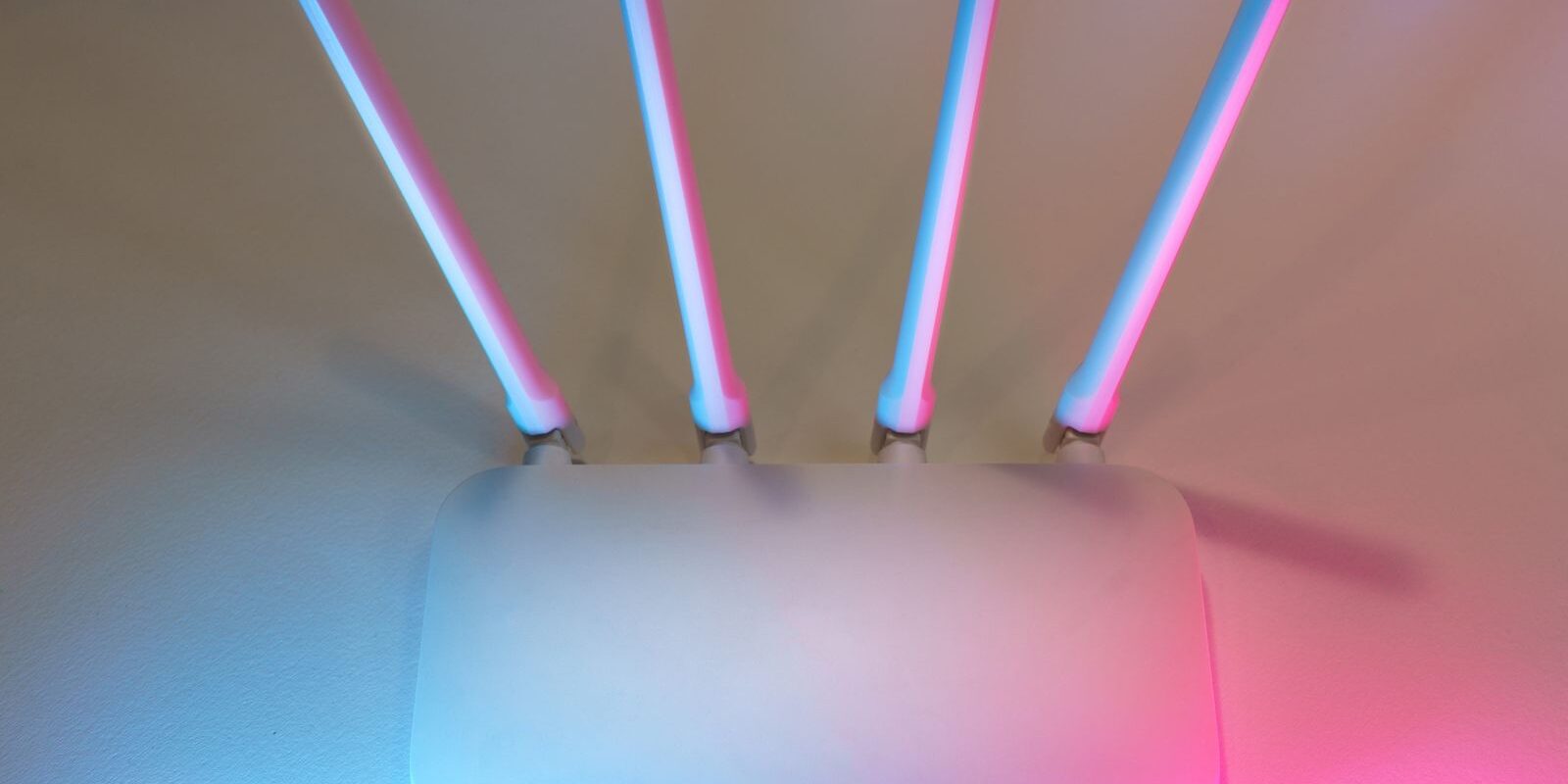 Router inalámbrico blanco con cuatro antenas iluminado con luces rosa y azul