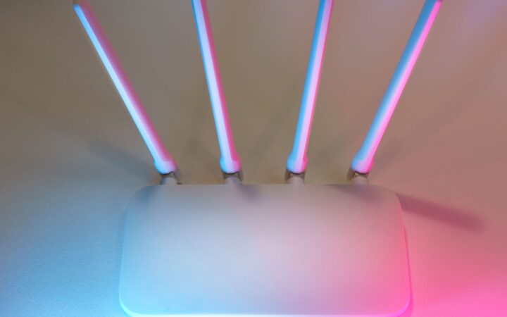 Router inalámbrico blanco con cuatro antenas iluminado con luces rosa y azul