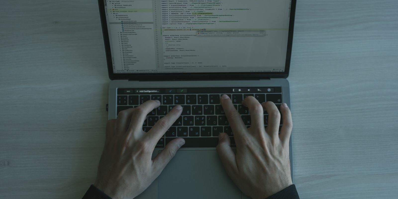 Manos de una persona escribiendo en el teclado de una laptop con código en la pantalla
