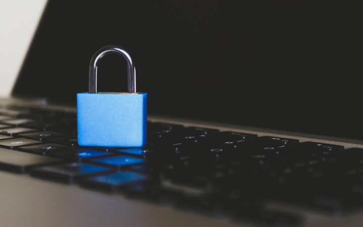 Candado azul cerrado sobre el teclado de una laptop oscura