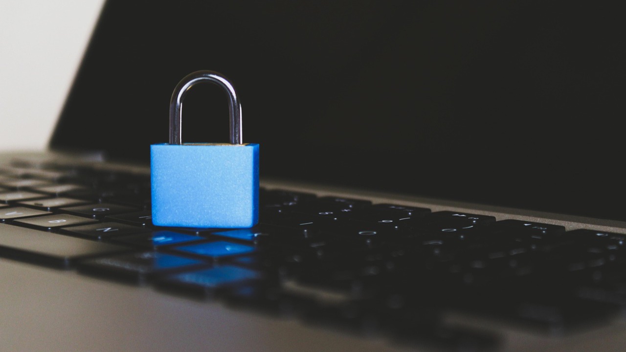 Candado azul cerrado sobre el teclado de una laptop oscura
