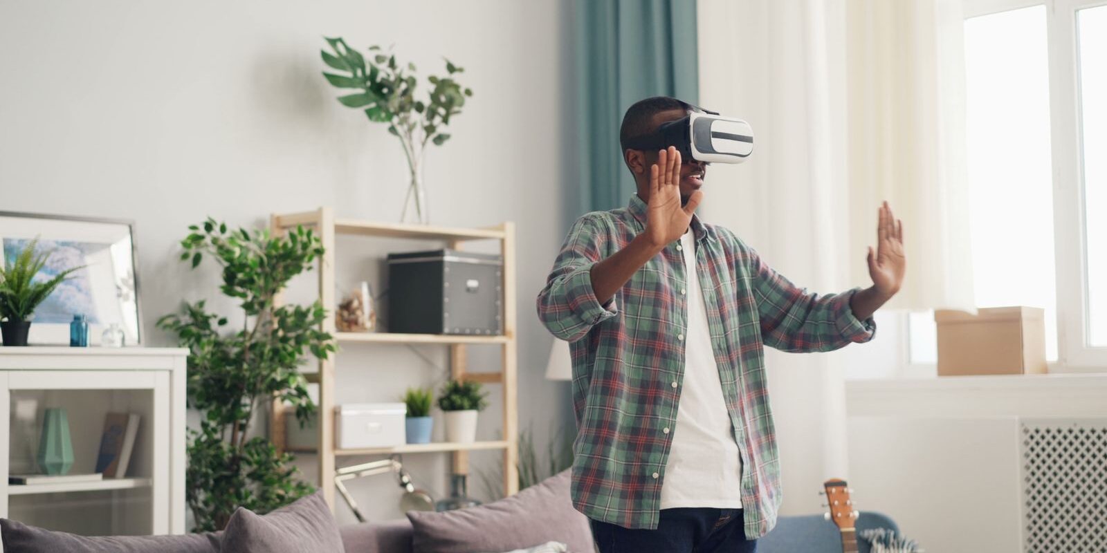 Hombre con visor de realidad virtual moviendo las manos en una sala iluminada