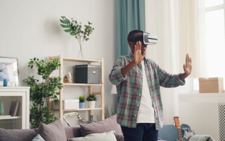Hombre con visor de realidad virtual moviendo las manos en una sala iluminada