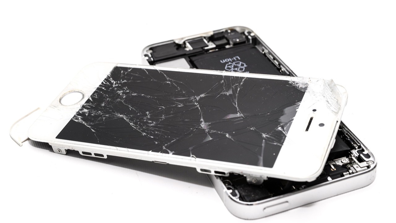 Celular desarmado con la pantalla estrellada separada del cuerpo, listo para reparación