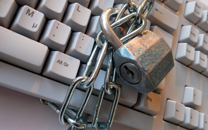 Candado metálico con una cadena sobre un teclado de computadora de color claro