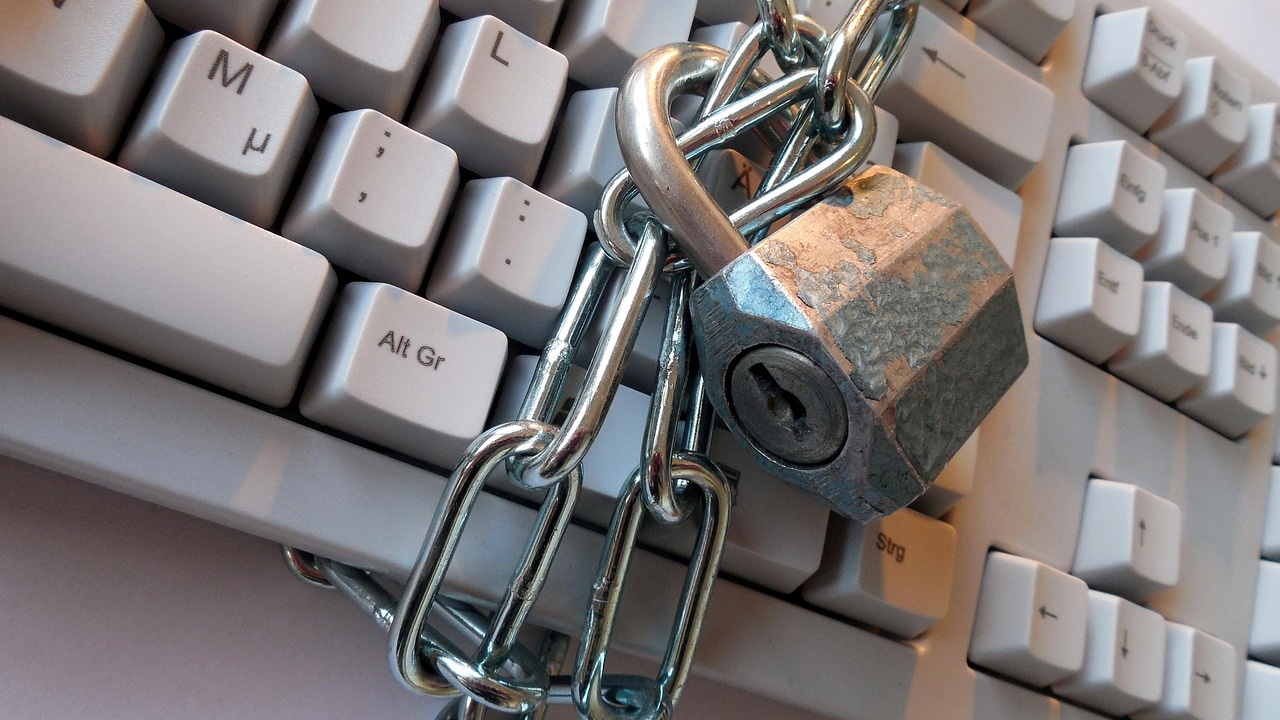 Candado metálico con una cadena sobre un teclado de computadora de color claro