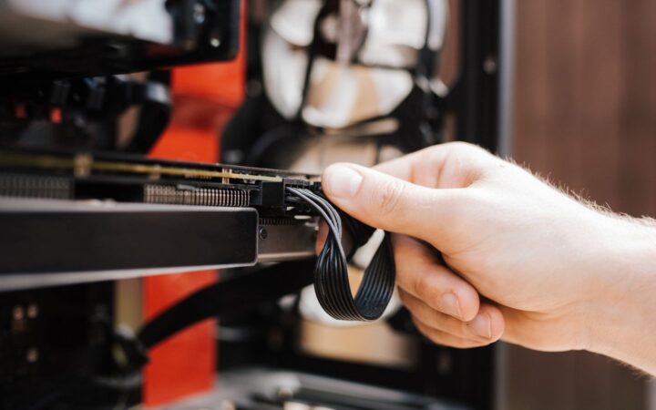 Mano conectando un cable de corriente a una tarjeta gráfica dentro de una computadora de escritorio