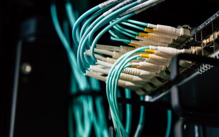 Cables de fibra óptica color turquesa conectados a un panel de servidor en un centro de datos