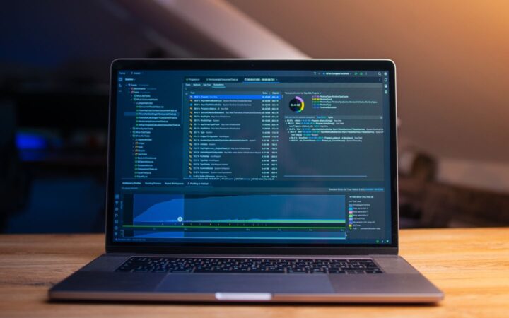 Laptop abierta sobre un escritorio de madera mostrando un entorno de desarrollo