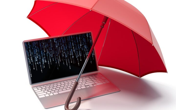 Laptop protegida bajo un paraguas rojo sobre un fondo blanco